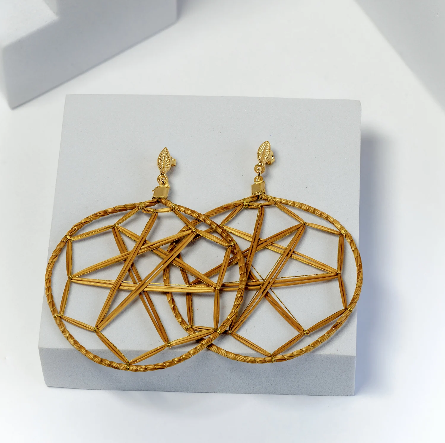 Geometric earrings displayed on a pale jewellery stand.